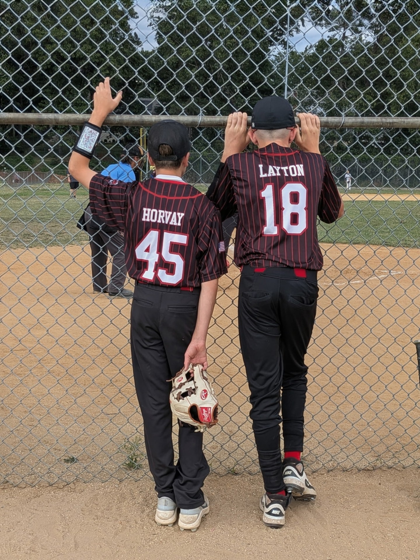Two Crimson Tide players watching the action through the dugout fence