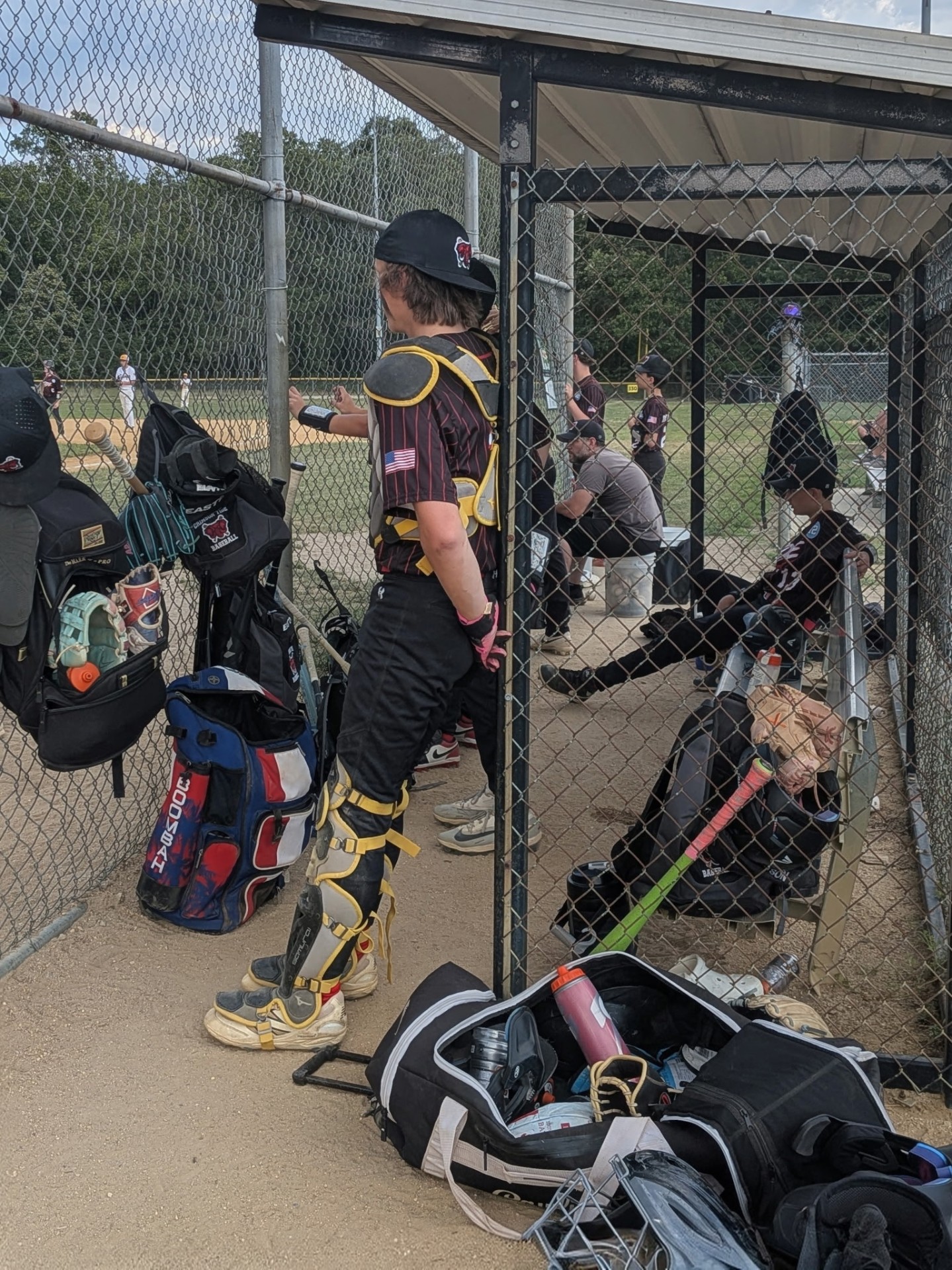 Crimson Tide catcher in full gear watching the field from the dugout